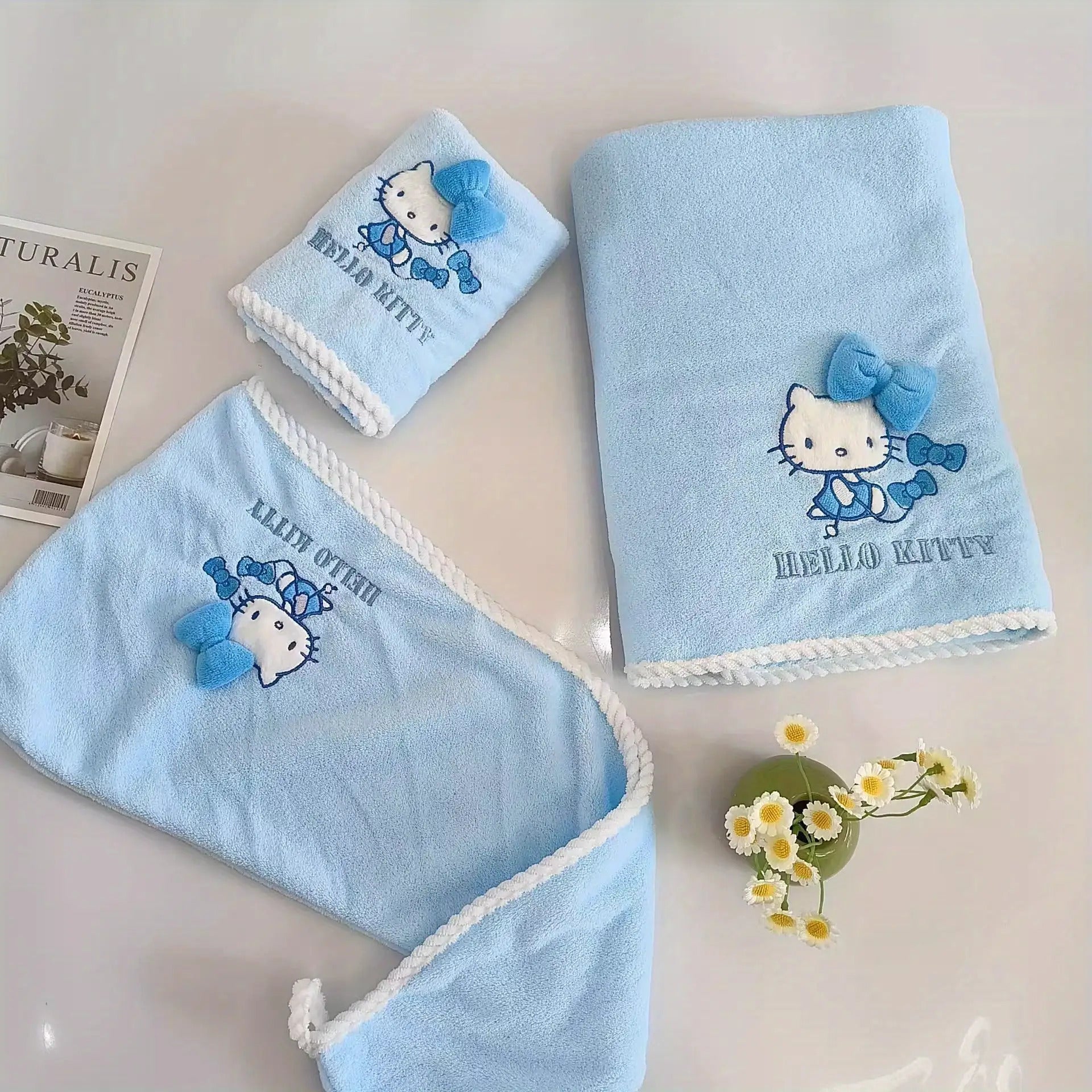 A Set of Three Sanrio Towels Themed Around for Hello Kitty, Including Bath Towels, Face Towels, And a Hair Drying Cap, All Showcasing a Three-Dimensional for Hello Kitty Design